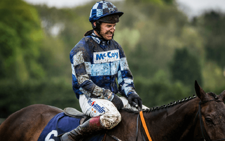 Champion Jockey Richard Johnson sat on his horse covered in mud at the end of a race.